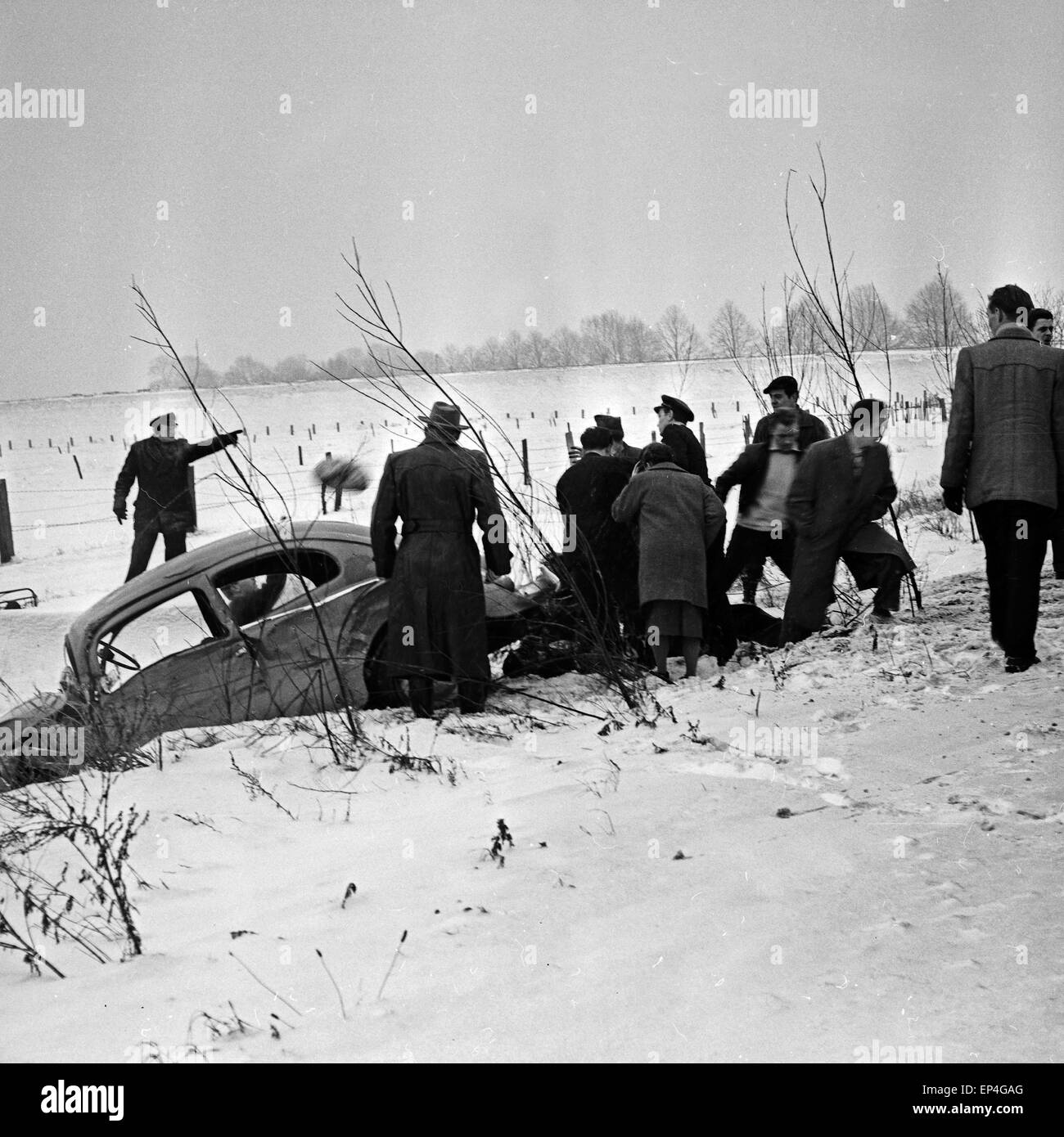 Ein VW Käfer ist bei einem Verkehrsunfall bei Schnee in den Straßengraben gerutscht, Deutschland 1960er Jahre. A Volkswagen beet Stock Photo