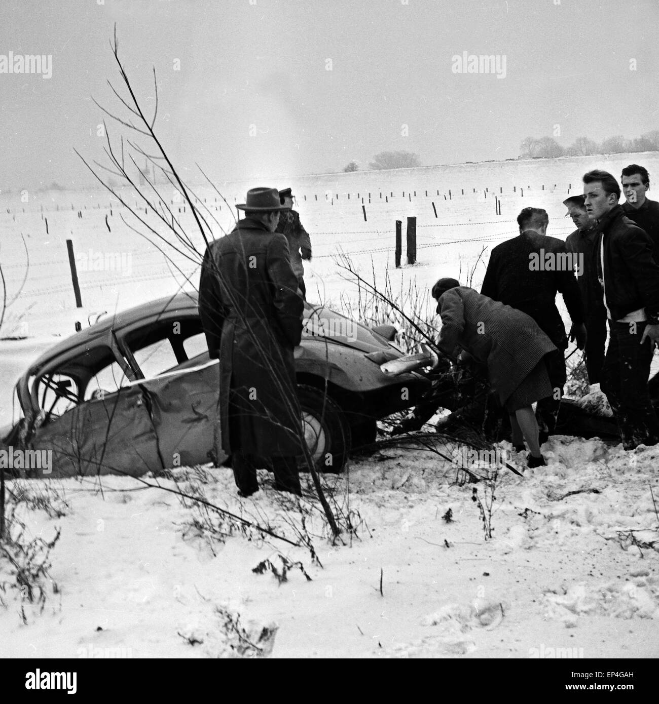 Ein VW Käfer ist bei einem Verkehrsunfall bei Schnee in den Straßengraben gerutscht, Deutschland 1960er Jahre. A Volkswagen beet Stock Photo