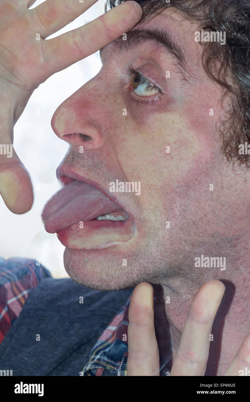 Crazy lunatic man smooshes face against glass surfaces Stock Photo
