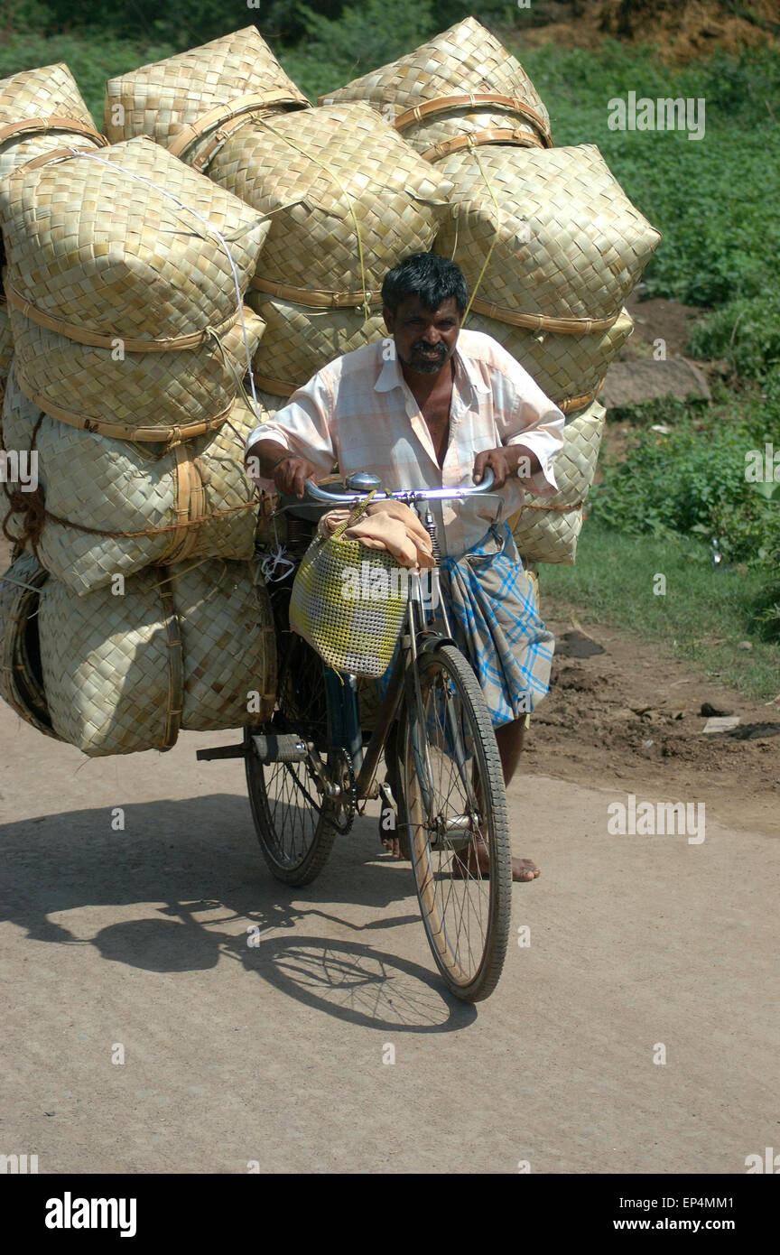 TAMIL NADU, INDIA, circa 2009: An unidentified man and his overloaded bike head to town, circa 2009 in Tamil Nadu, India. Stock Photo