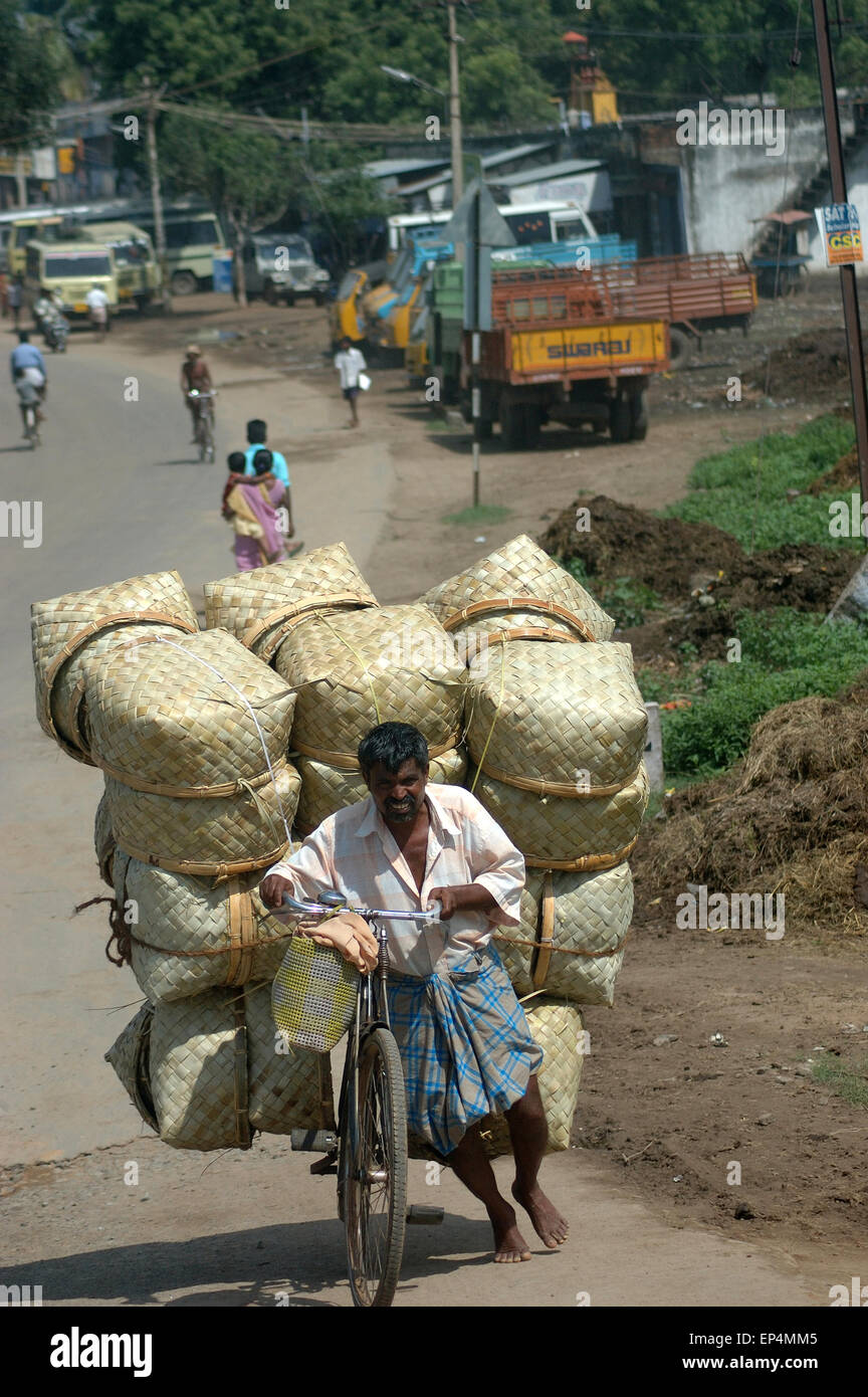 TAMIL NADU, INDIA, circa 2009: An unidentified man and his overloaded bike head to town, circa 2009 in Tamil Nadu, India. Stock Photo