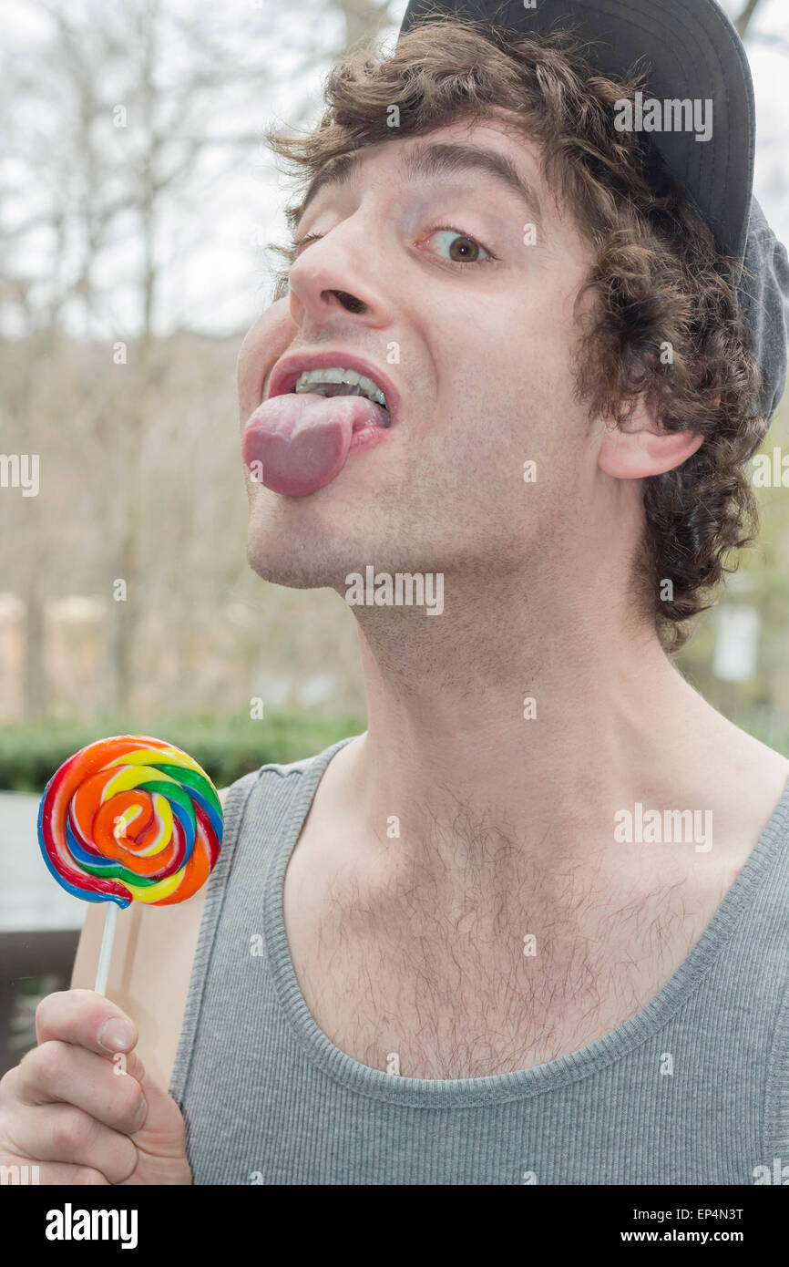 Silly man licks the glass instead of his lollipop in this funny childish photo Stock Photo