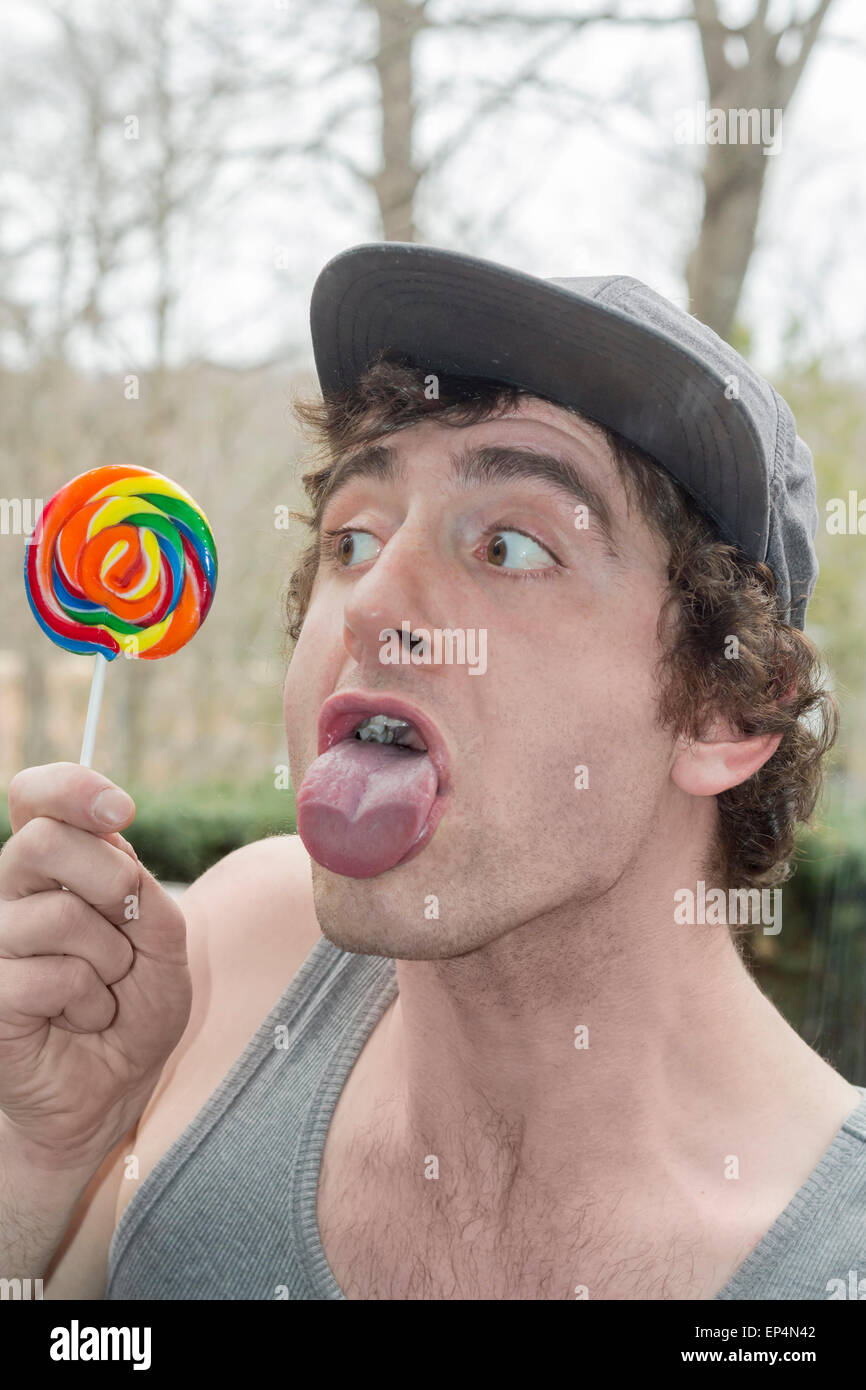 Silly man licks the glass instead of his lollipop in this funny childish photo Stock Photo