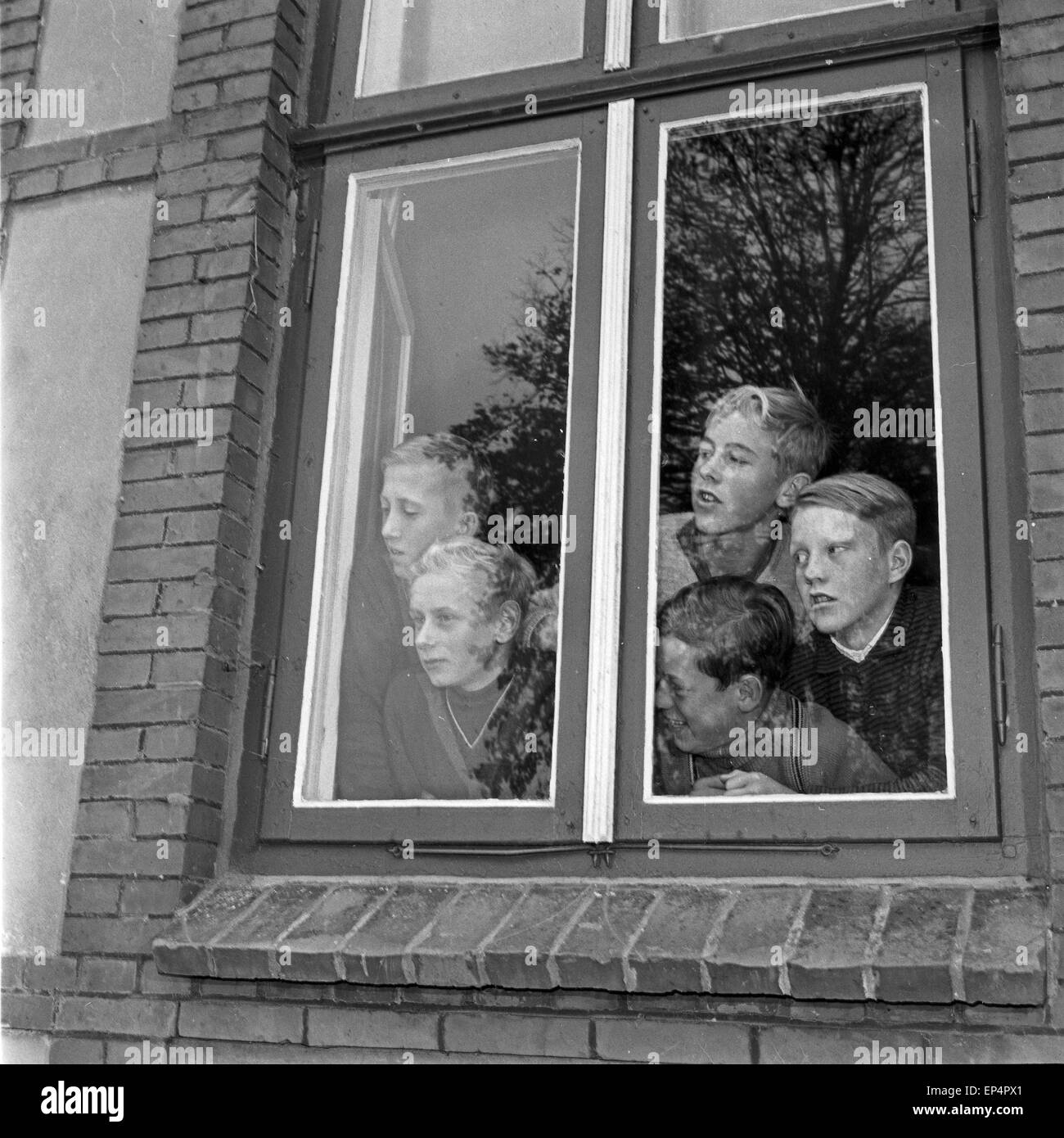 Neugierig hängen die Kinder am Fenster vom Schulgebäude in Lüdersbüttel im Kreis Norderdithmarschen in Schleswig Holstein am Tag Stock Photo