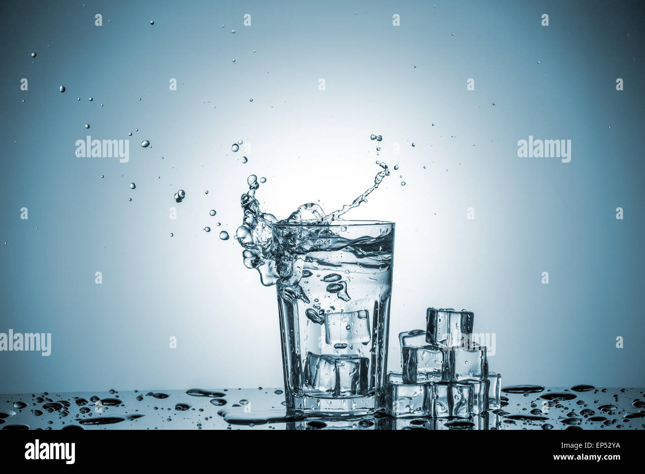 ice cubes falling into a glass of water and ice cubes, lying next, on ...