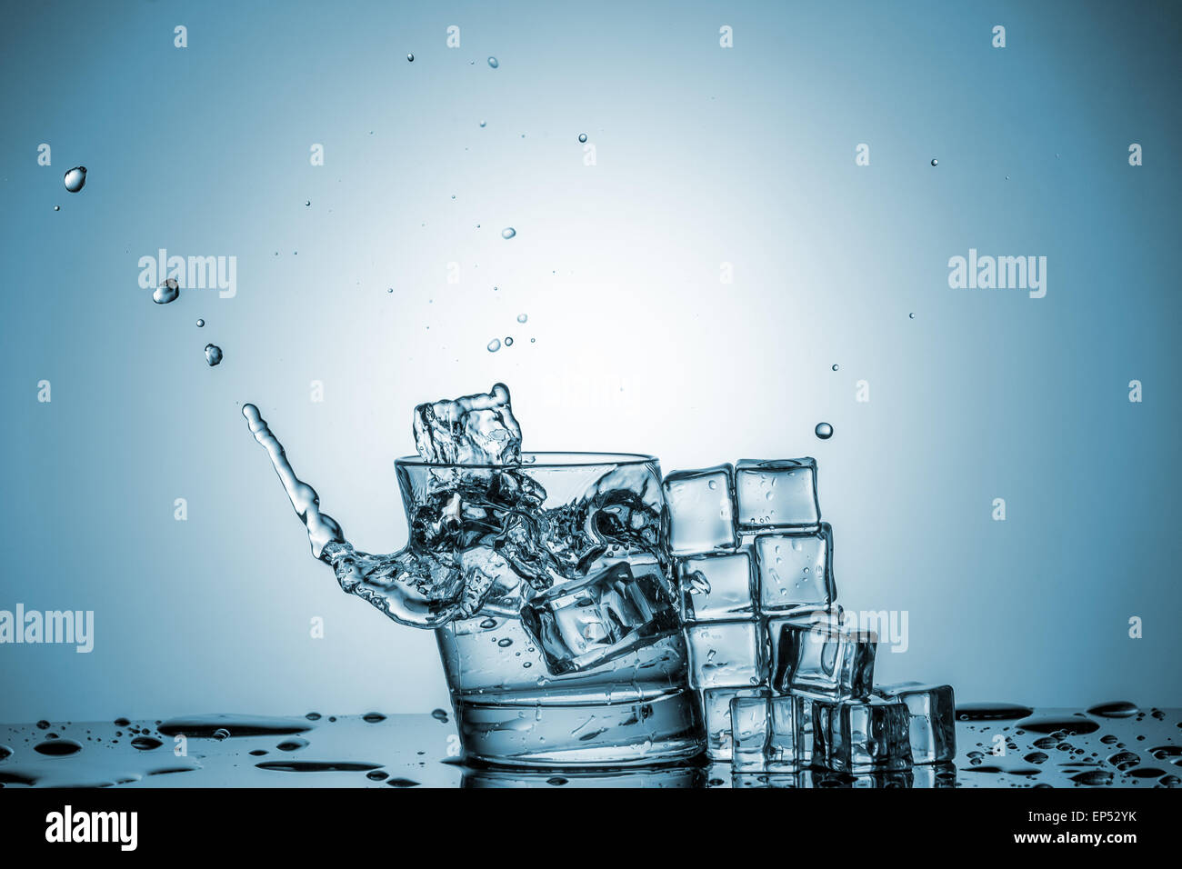 ice cubes falling into a glass of water and ice cubes, lying next, on ...