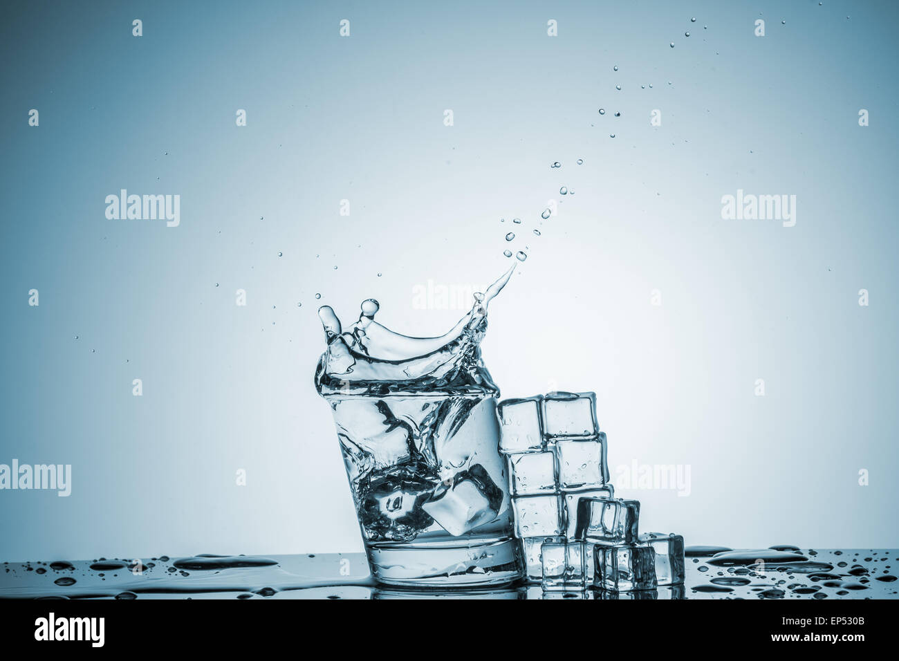 ice cubes falling into a glass of water and ice cubes, lying next, on ...