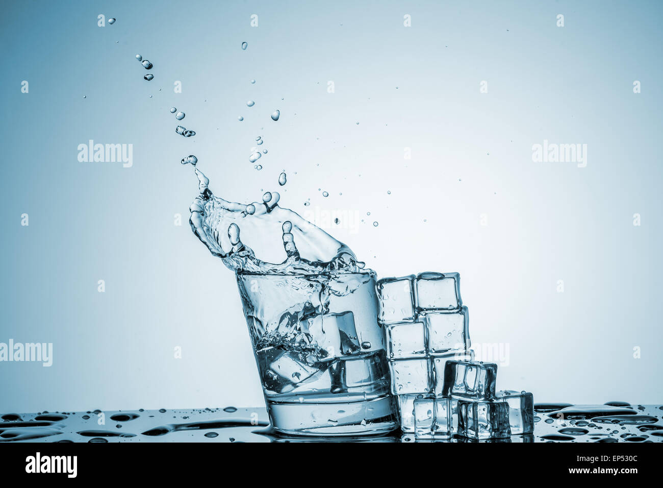 ice cubes falling into a glass of water and ice cubes, lying next, on ...
