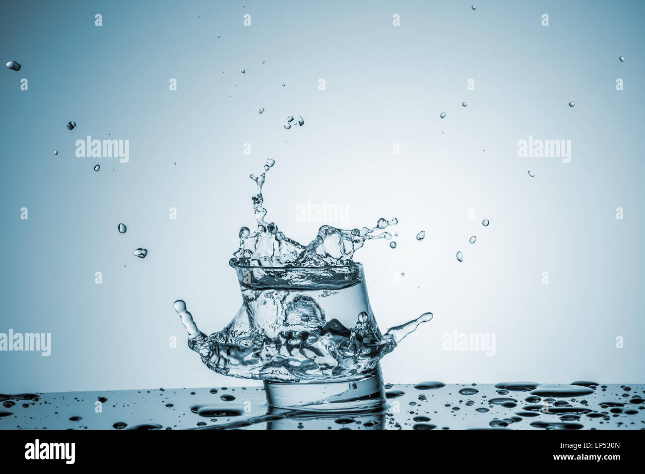ice cube falling into a glass of water on blue background Stock Photo ...
