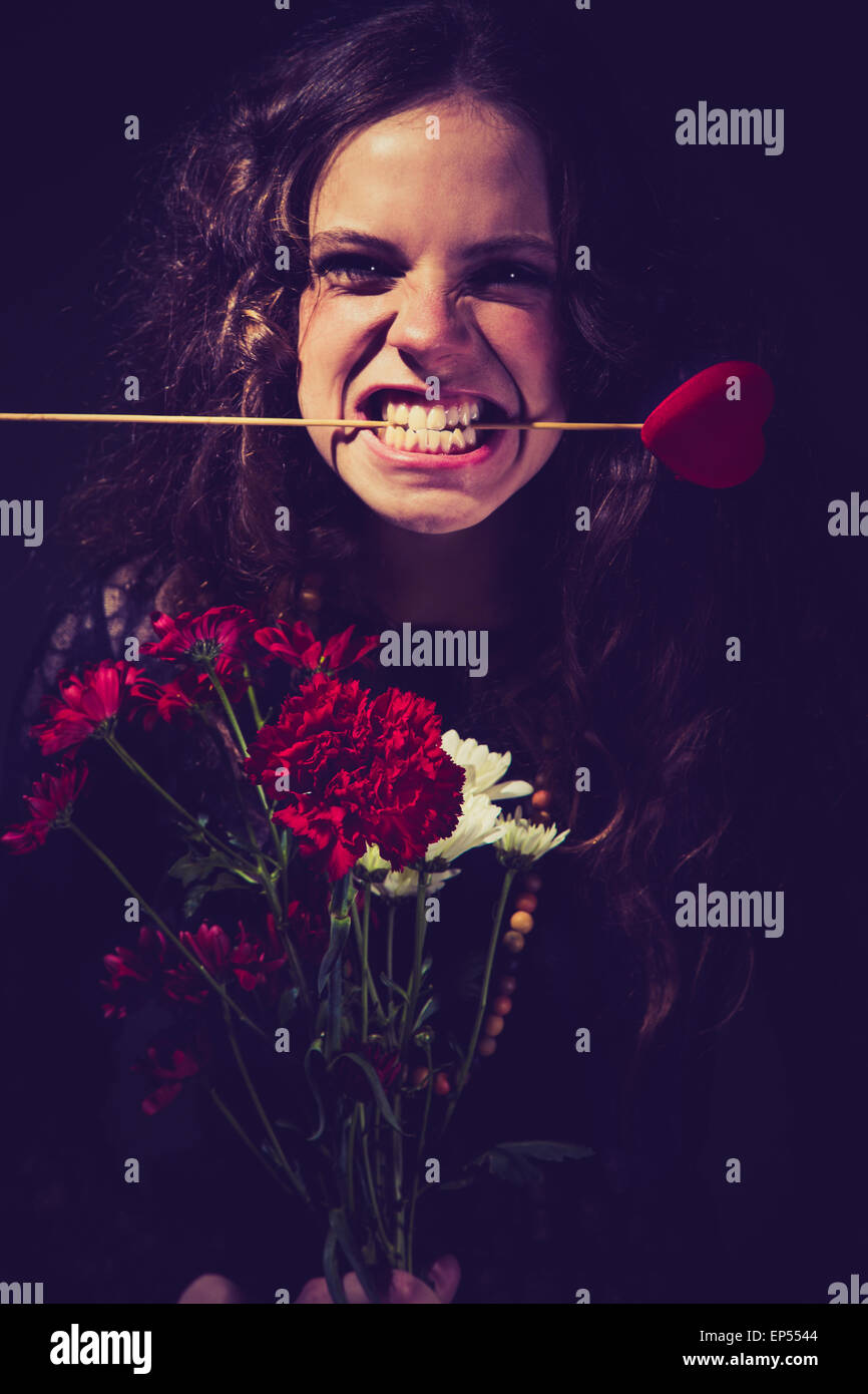 A young woman with flowers in her hands and a grimace on her face. Who has let down this beauty on Valentine's Day? Stock Photo