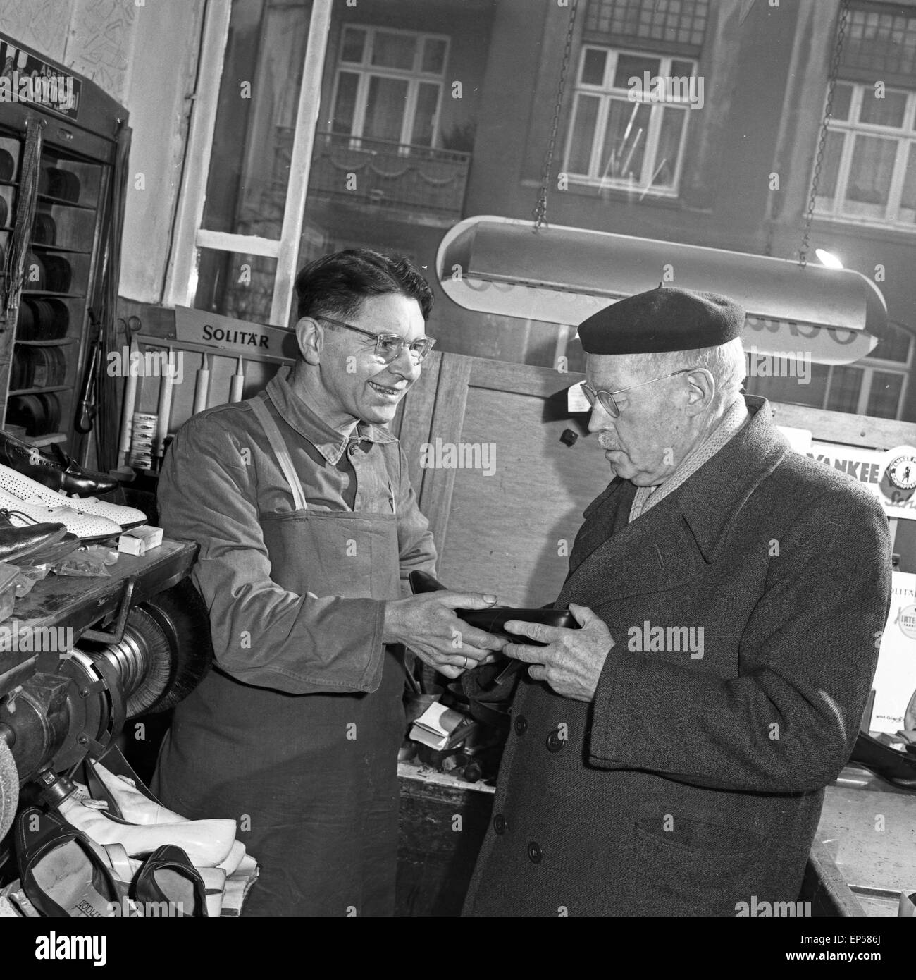Ein älterer Herr holt beim Schuster ein Paar Schuhe ab, Deutschland 1960er Jahre. An elder man taking a pair of shoes from the s Stock Photo