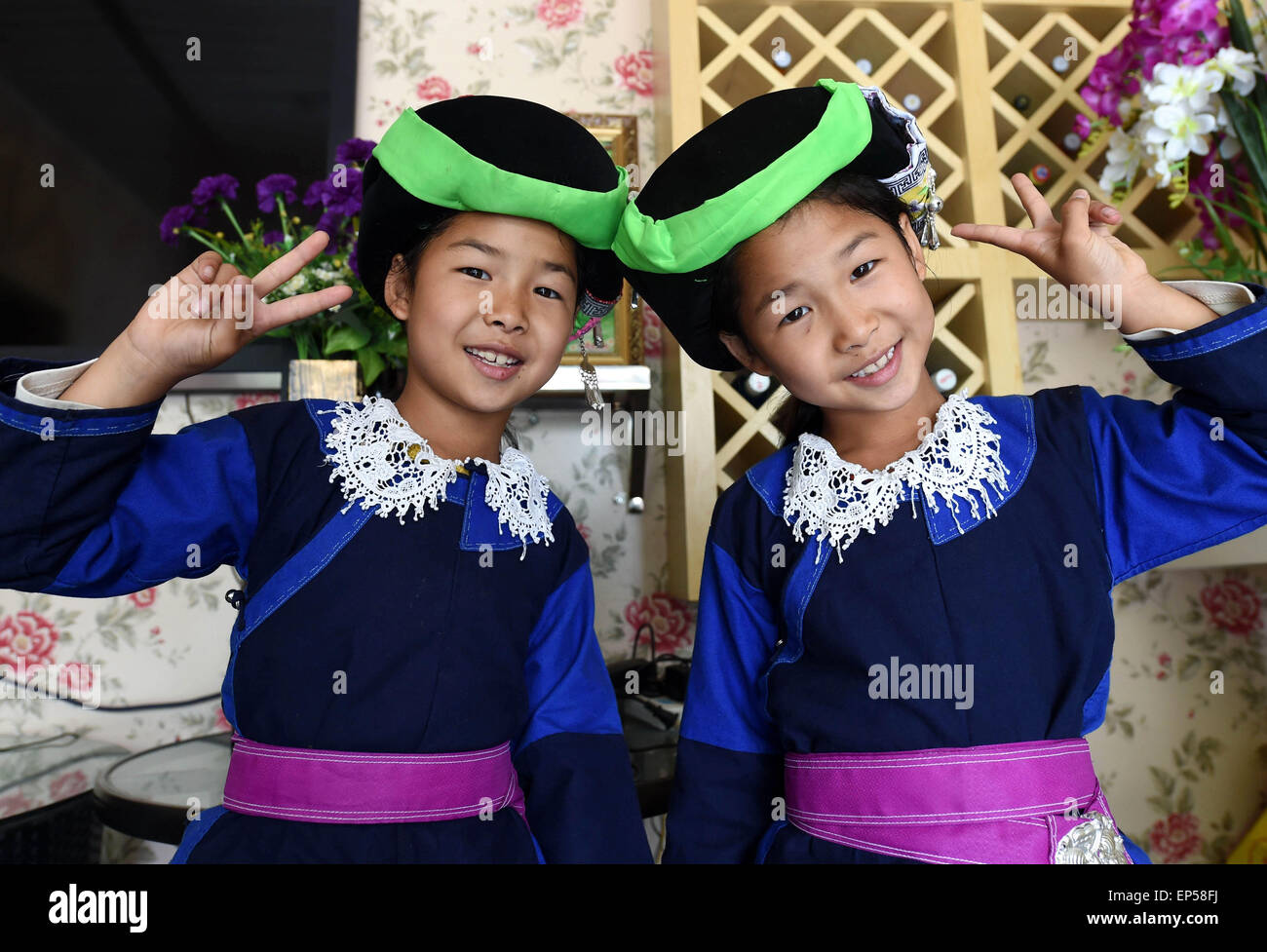 (150514) -- MOJIANG, May 14, 2015 (Xinhua) -- Twin sisters Jin Meixian (R) and Jin Huixian wearing folk costumes pose for a group photo at home in Mojiang Hani Autonomous County, southwest China's Yunnan Province, May 12, 2015.    Twin sisters Jin Meixian and Jin Huixian, 7, live with their mother Wang Fei, who opens a cold drink store. Their father does business in another province.    Meixian, the older, loves music and wants to be a musical teacher. Huixian likes dancing, and wants to go to college in Beijing. 'We always feel connected. Sometimes we find out that we are singing the same son Stock Photo
