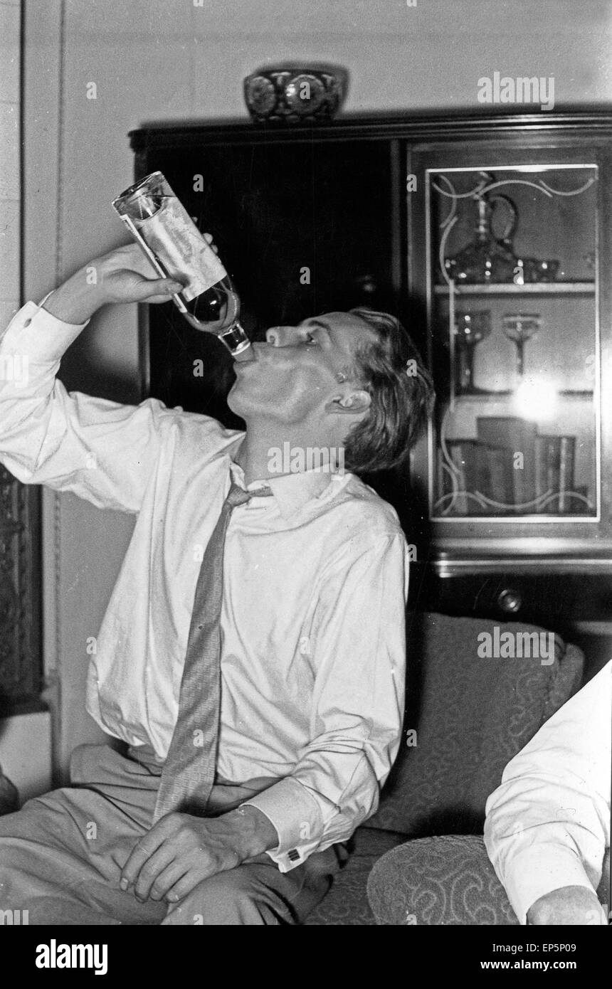 Ein junger Mann trinkt Schnaps aus der Flasche, Deutschland Anfang 1960er  Jahre. A young man boozing, Germany early 1960s Stock Photo - Alamy