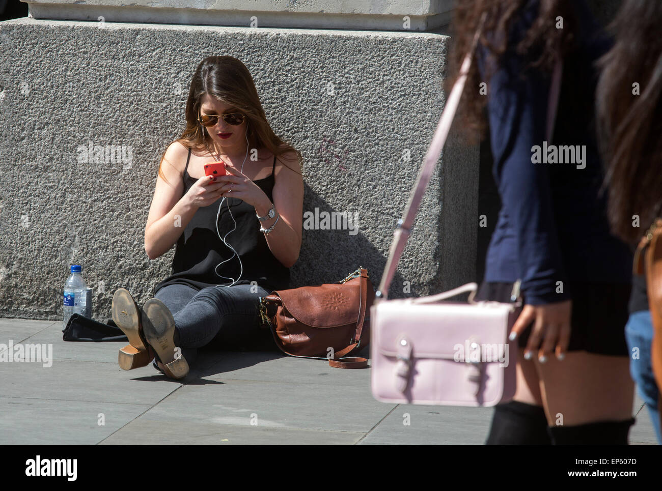 iphone mobile phone users user sun shine looking at their phones outside the Apple Store in Covent Garden Stock Photo