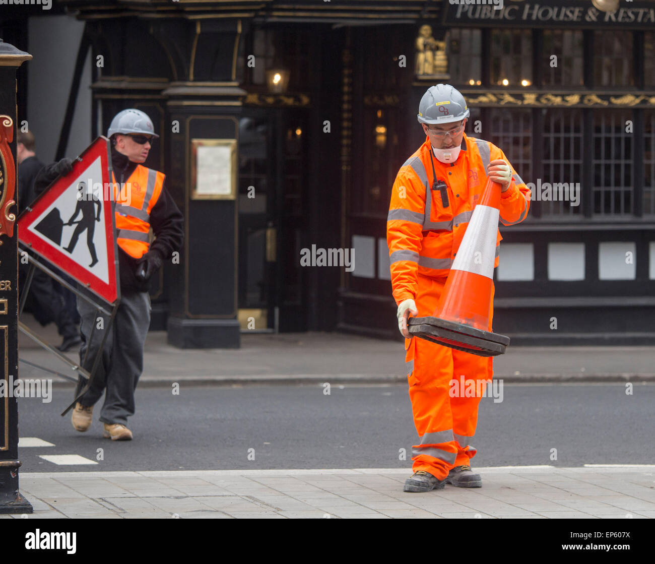 Man carrying roadworks sign workman hard hat orange Stock Photo