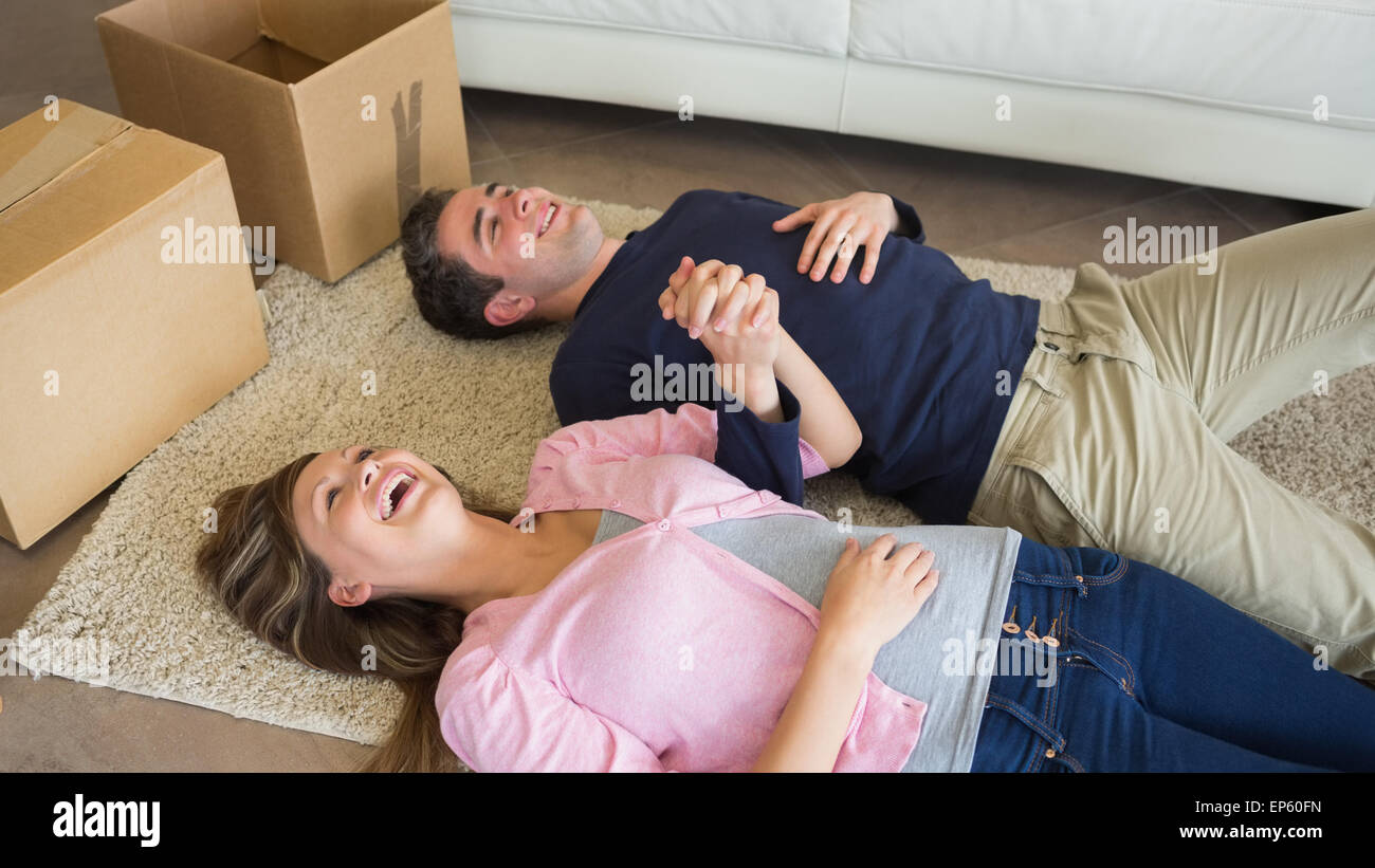 Laughing couple lying on floor with moving boxes Stock Photo