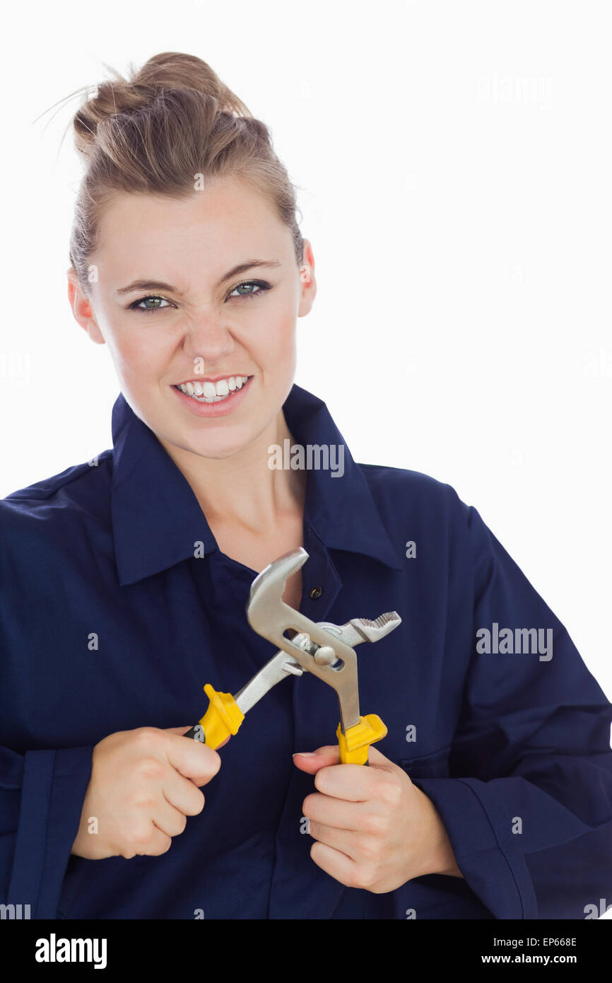 Female mechanic clenching teeth while holding pliers wrench Stock Photo
