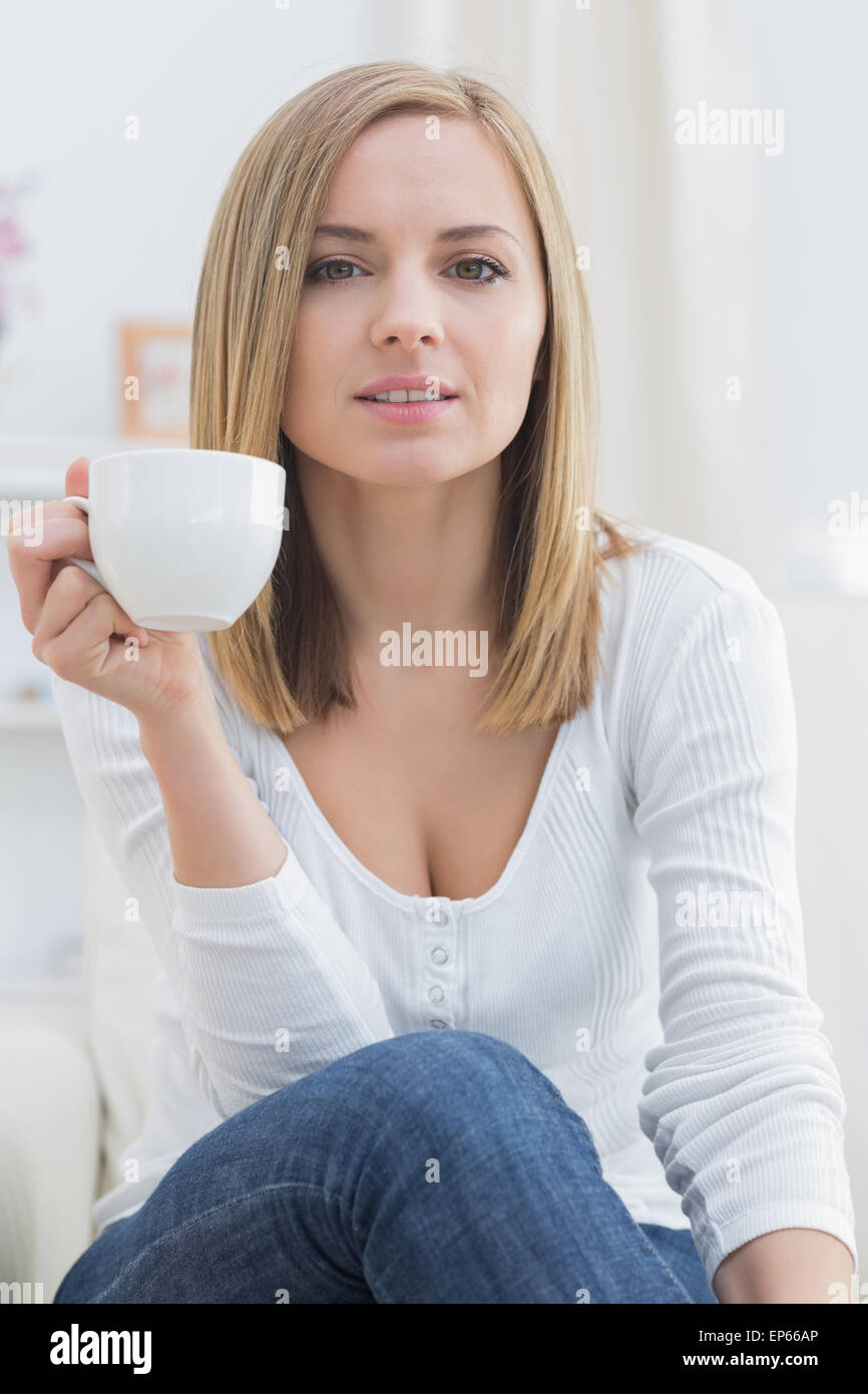 Young woman with coffee cup sitting on couch Stock Photo - Alamy