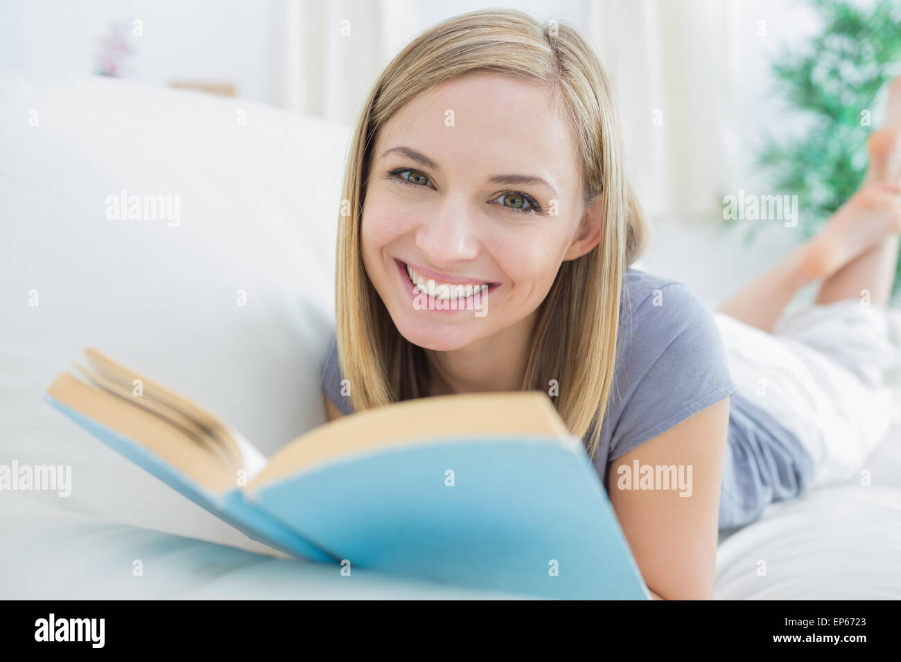 Portrait of happy woman with storybook lying on couch Stock Photo - Alamy