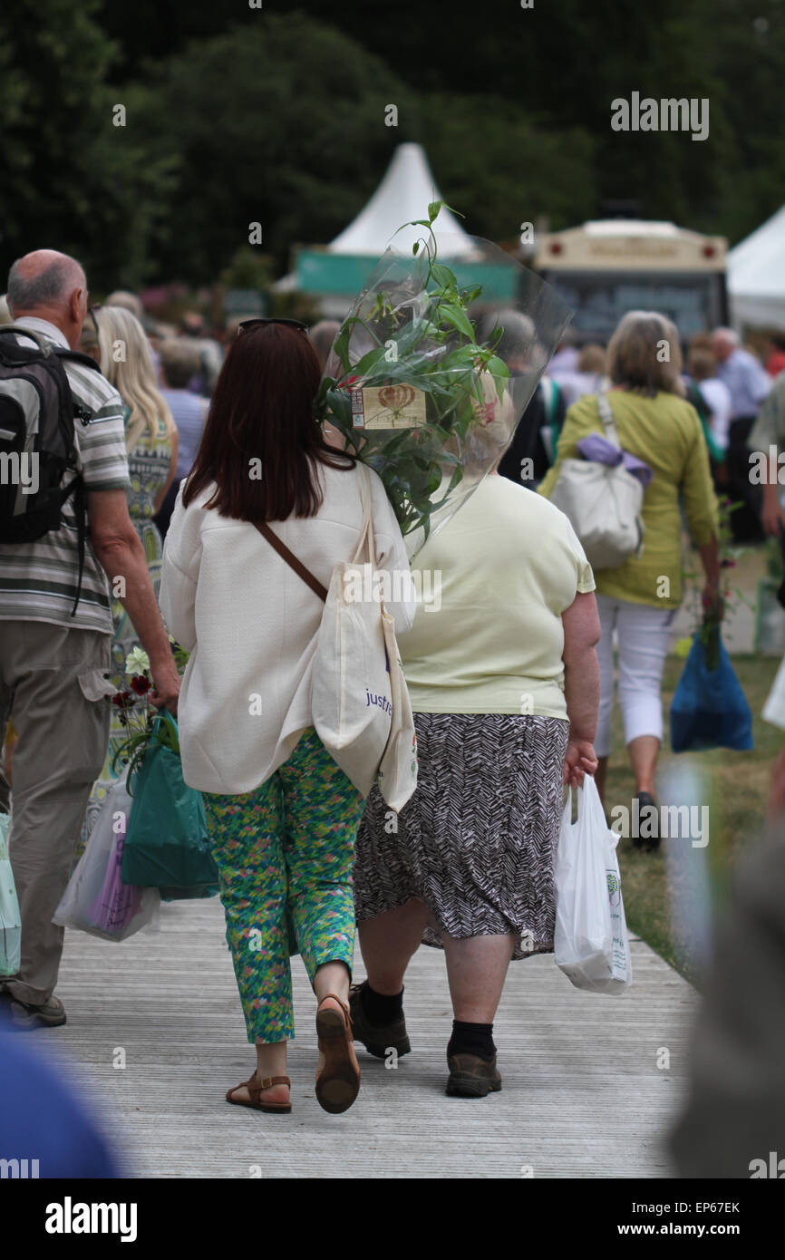 Female shoppers buying and carrying plants and flowers at RHS Hampton Court Flower Show, July 2014 Stock Photo