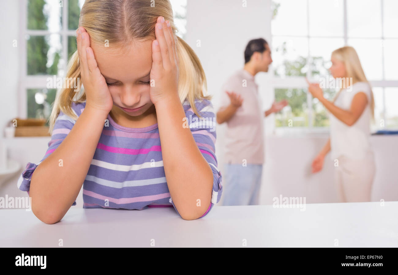 Little girl looking depressed in front of fighting parents Stock Photo