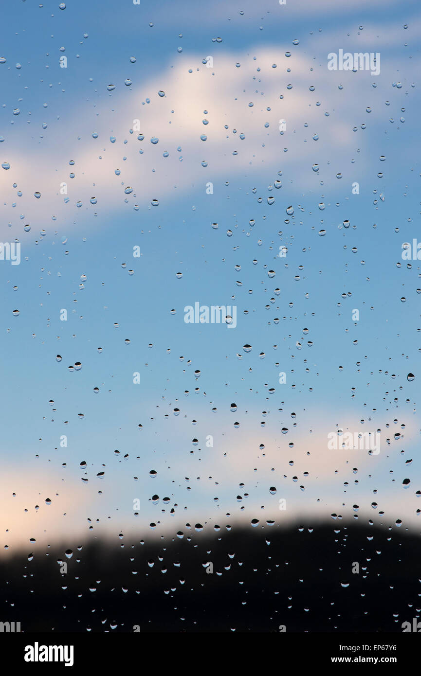 Raindrops on a window pane infront of a blue sky Stock Photo
