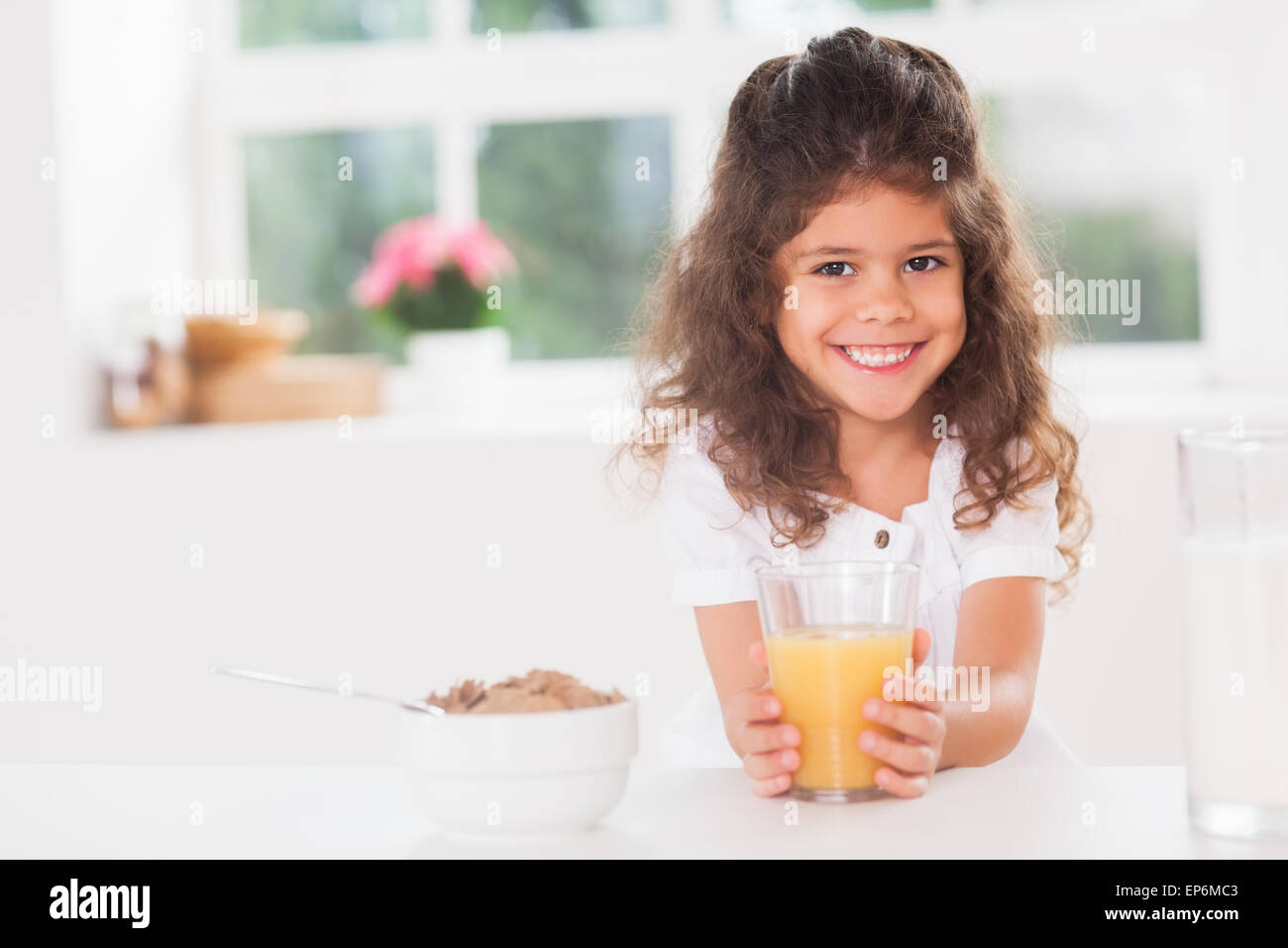 Little girl smiling with her orange juice in hand Stock Photo - Alamy