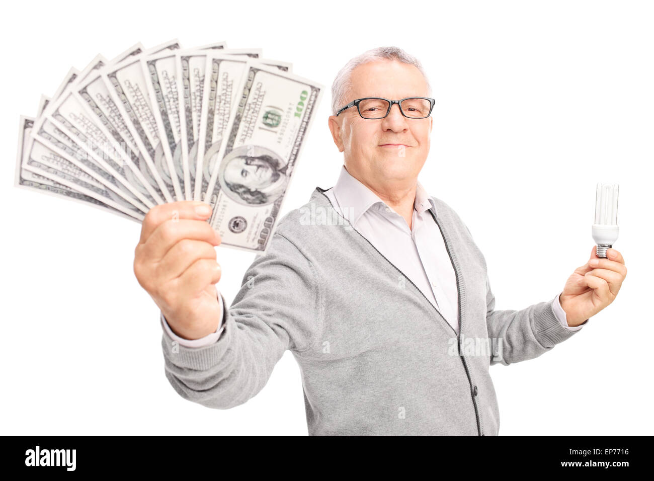 Economic senior holding an energy efficient light bulb and a stack of money isolated on white background Stock Photo