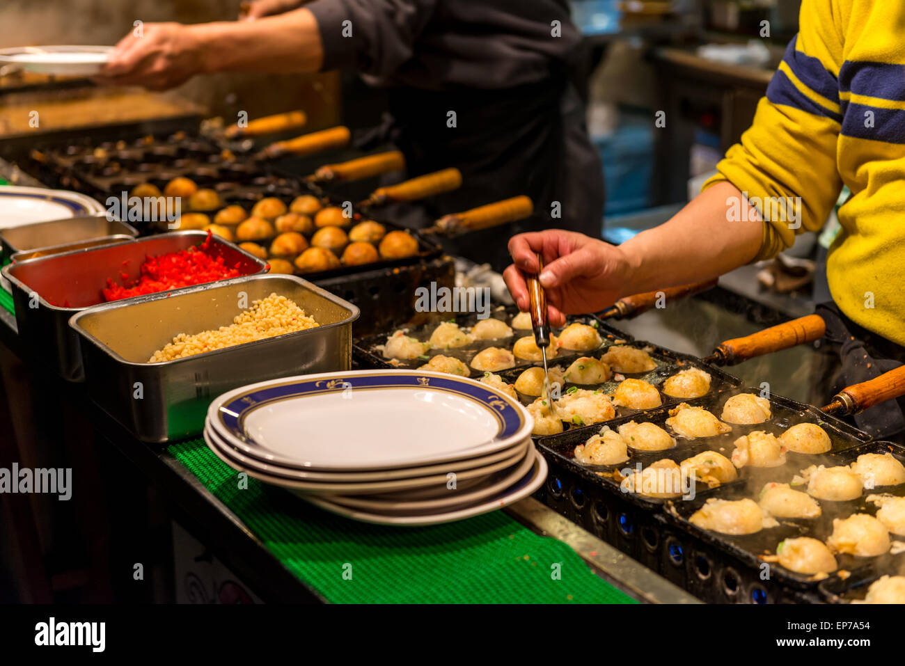 Japanese chefs prepare takoyaki and other snack foods at a stall in Osaka, Japan. Stock Photo