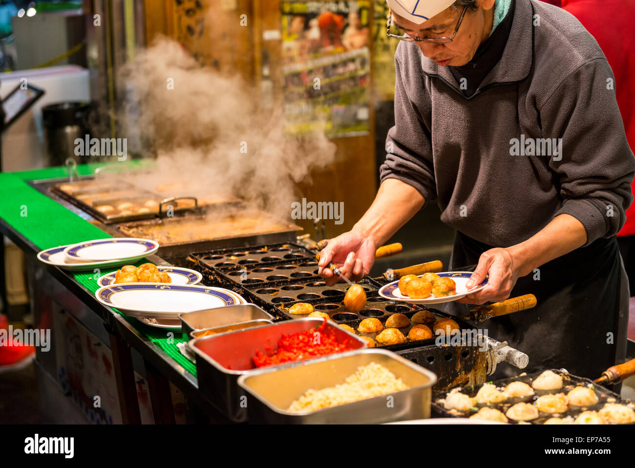 A Japanese man grills takoyaki at a food stall on December 27, 2014 in Osaka, Japan. Stock Photo