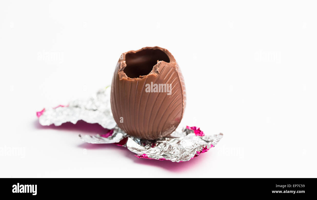 Easter egg unwrapped in pink foil with bite taken out Stock Photo
