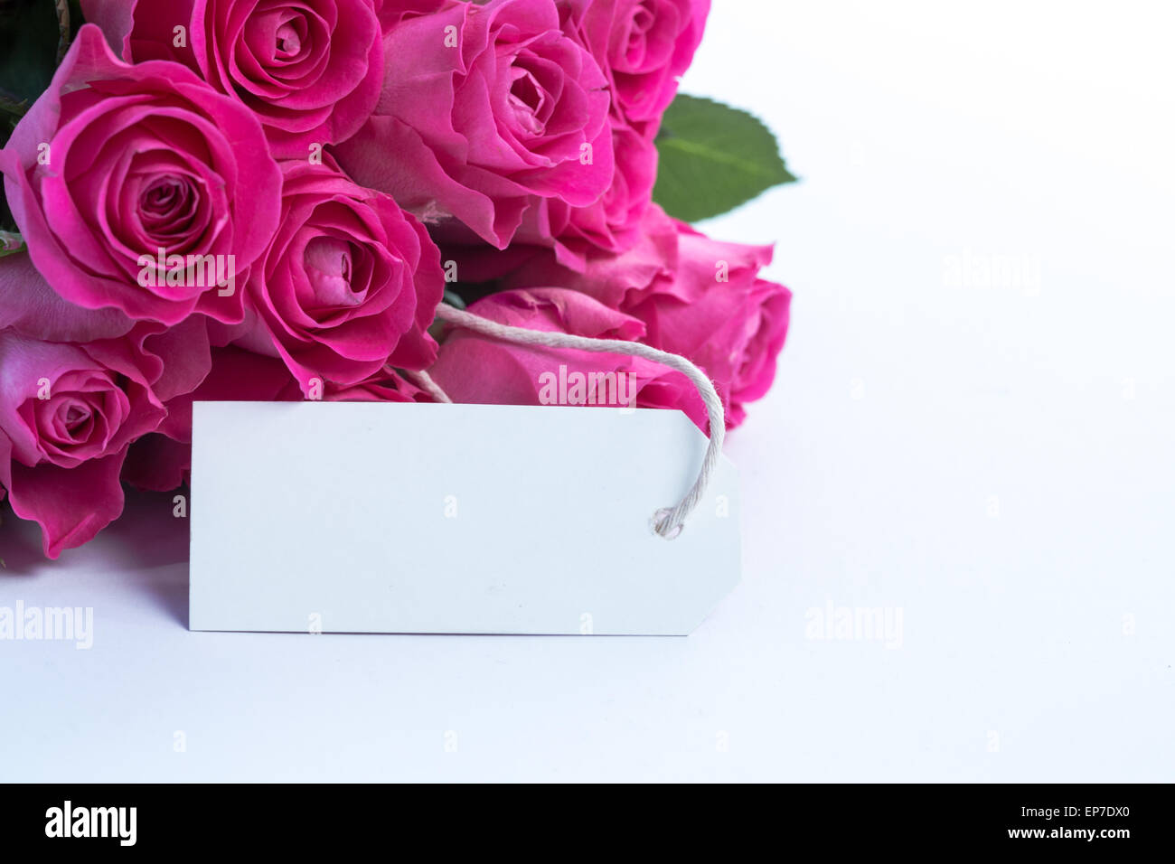 Bouquet of beautiful pink roses with an empty card on a table Stock Photo