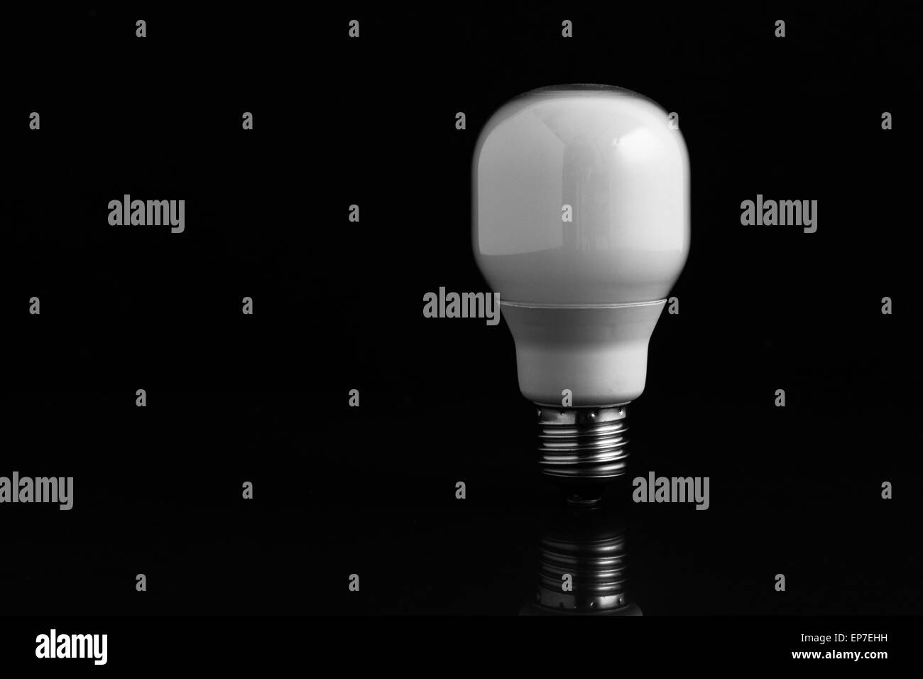 Energy saving bulb standing on black background Stock Photo - Alamy