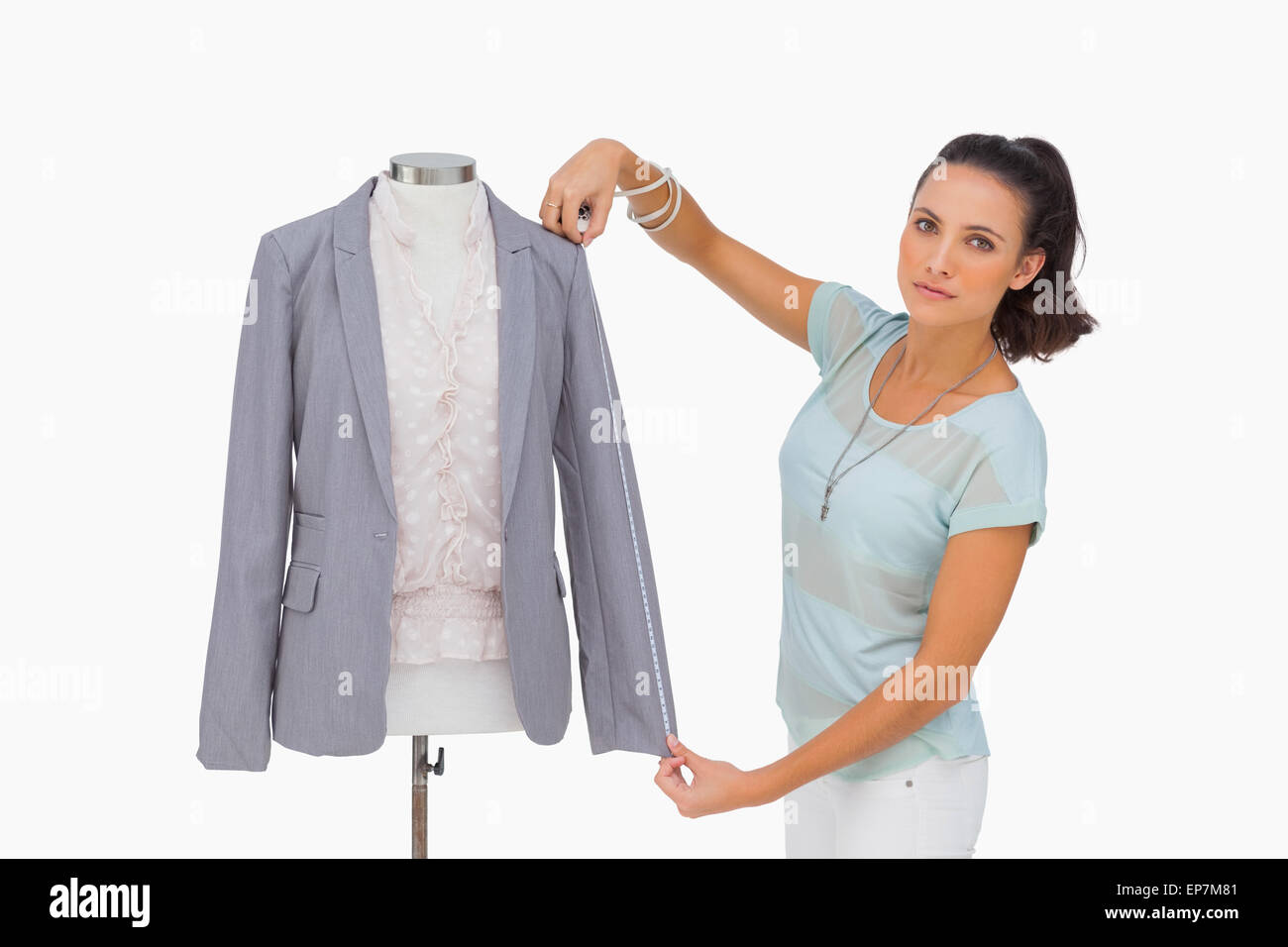 Fashion designer measuring blazer sleeve on mannequin and looking at ...
