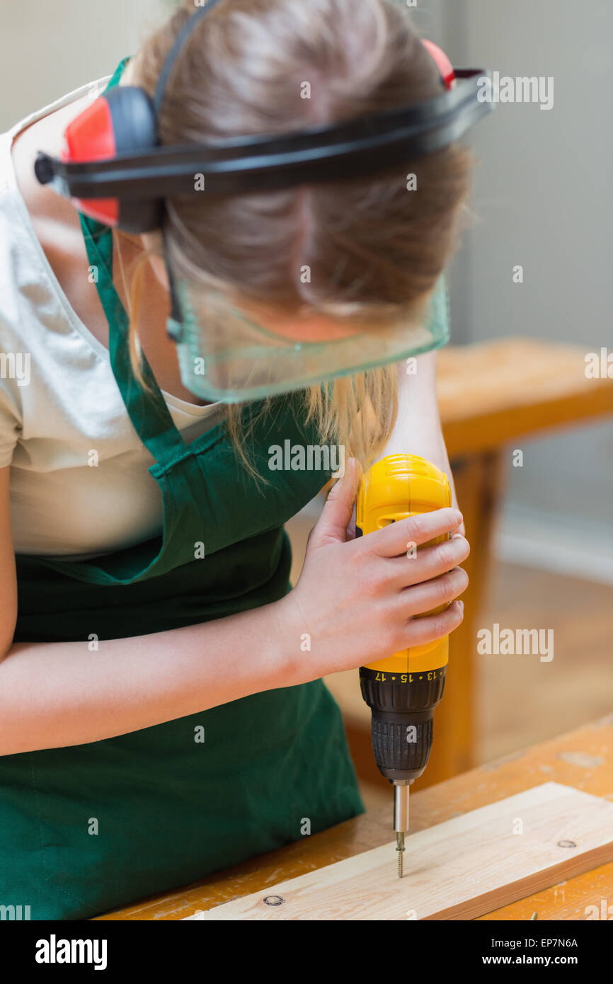 Student drilling a hole in a wooden board at the workbench Stock Photo