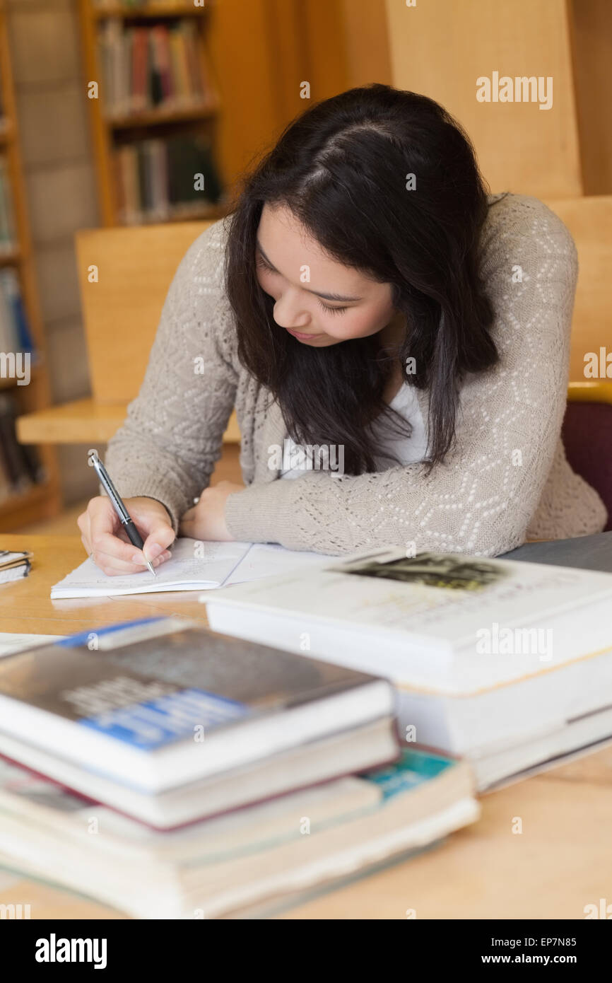 Student sitting in a library at a desk and writing Stock Photo - Alamy