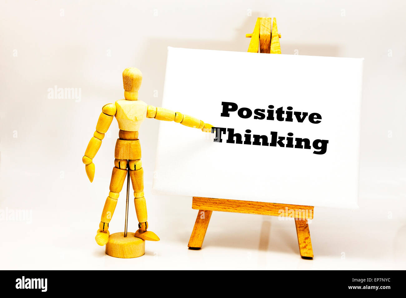 Wooden man with white board pointing at words 'Positive Thinking' using mind to control patterns affirmations attitude outlook Stock Photo