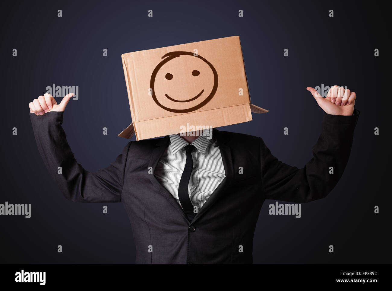 Businessman gesturing with a cardboard box on his head with smiley face ...