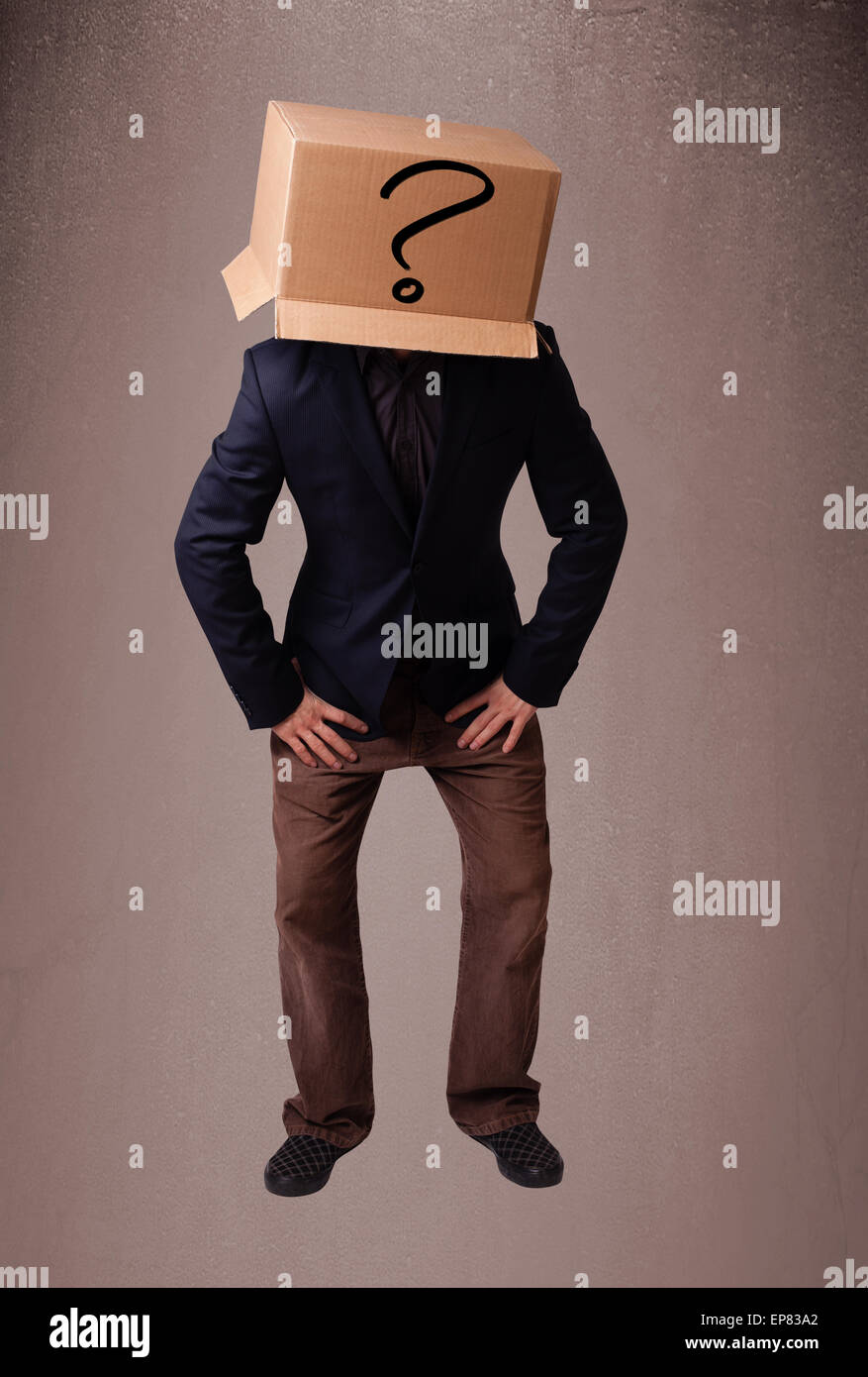 Young man gesturing with a cardboard box on his head with question mark ...