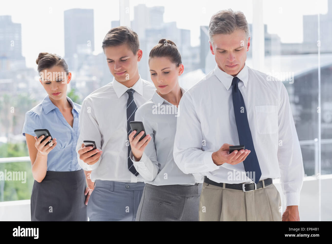 Serious business people standing together in line with their mobile ...