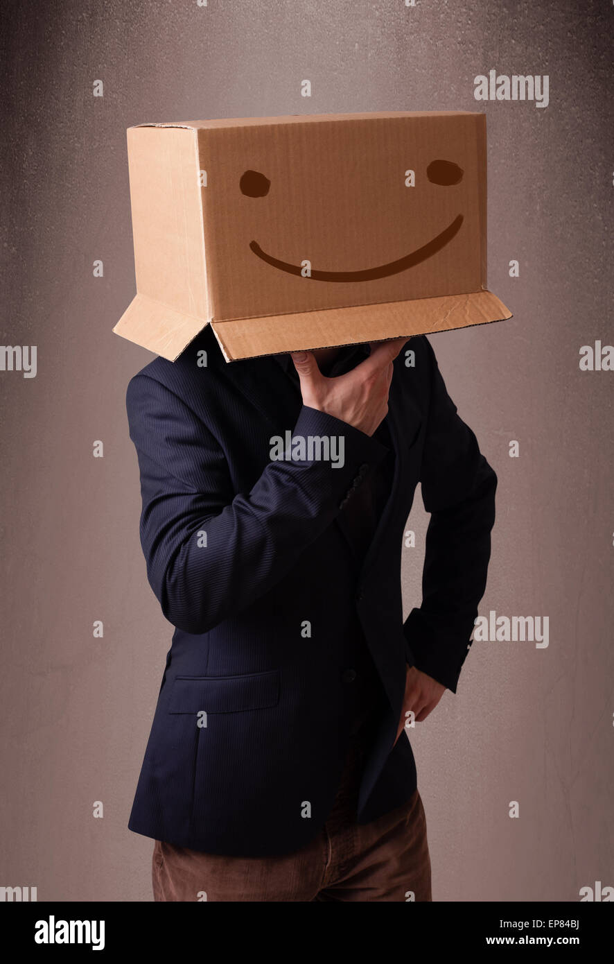Young man gesturing with a cardboard box on his head with smiley face ...