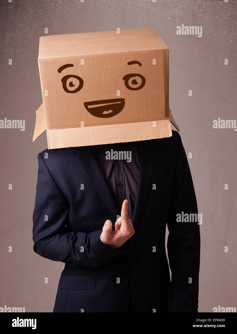 Young man gesturing with a cardboard box on his head with smiley face ...