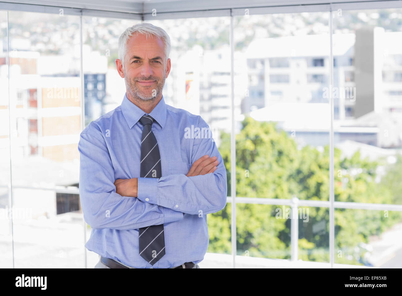 Businessman smiling at camera with arms crossed Stock Photo - Alamy