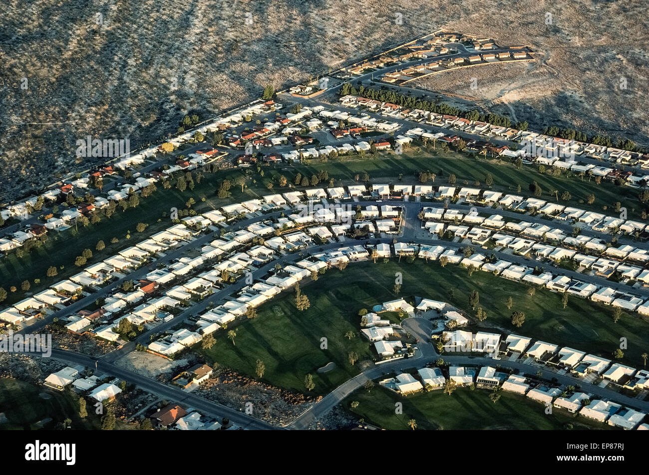 An aerial view shows the sun rising on a Palm Desert housing development in the Coachella Valley in Southern California, USA. This growing retirement haven east of Los Angeles includes the upscale communities of Rancho Mirage and La Quinta, as well as the famed desert resort city of Palm Springs. As one of the fastest growing areas of Riverside County, the Coachella Valley is projected to have a population that exceeds 600,000 residents by 2020. Stock Photo