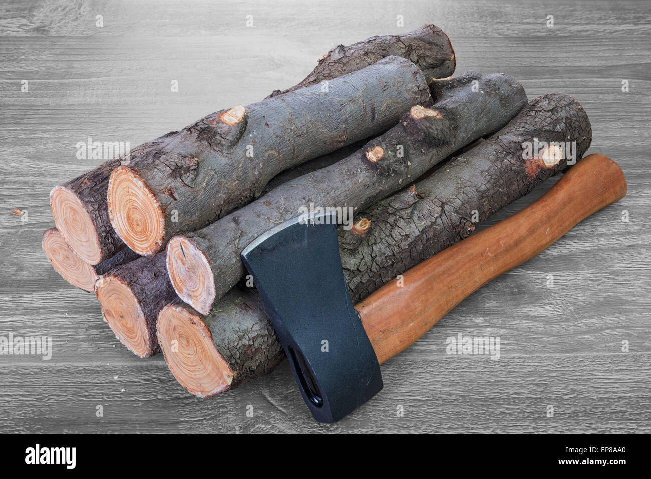 stack of firewood logs and axe on a wooden surface Stock Photo