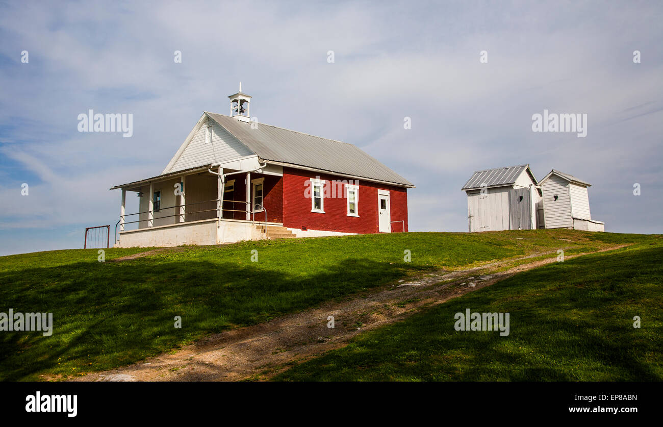 Historic red brick Amish one room schoolhouse exterior and outhouses in