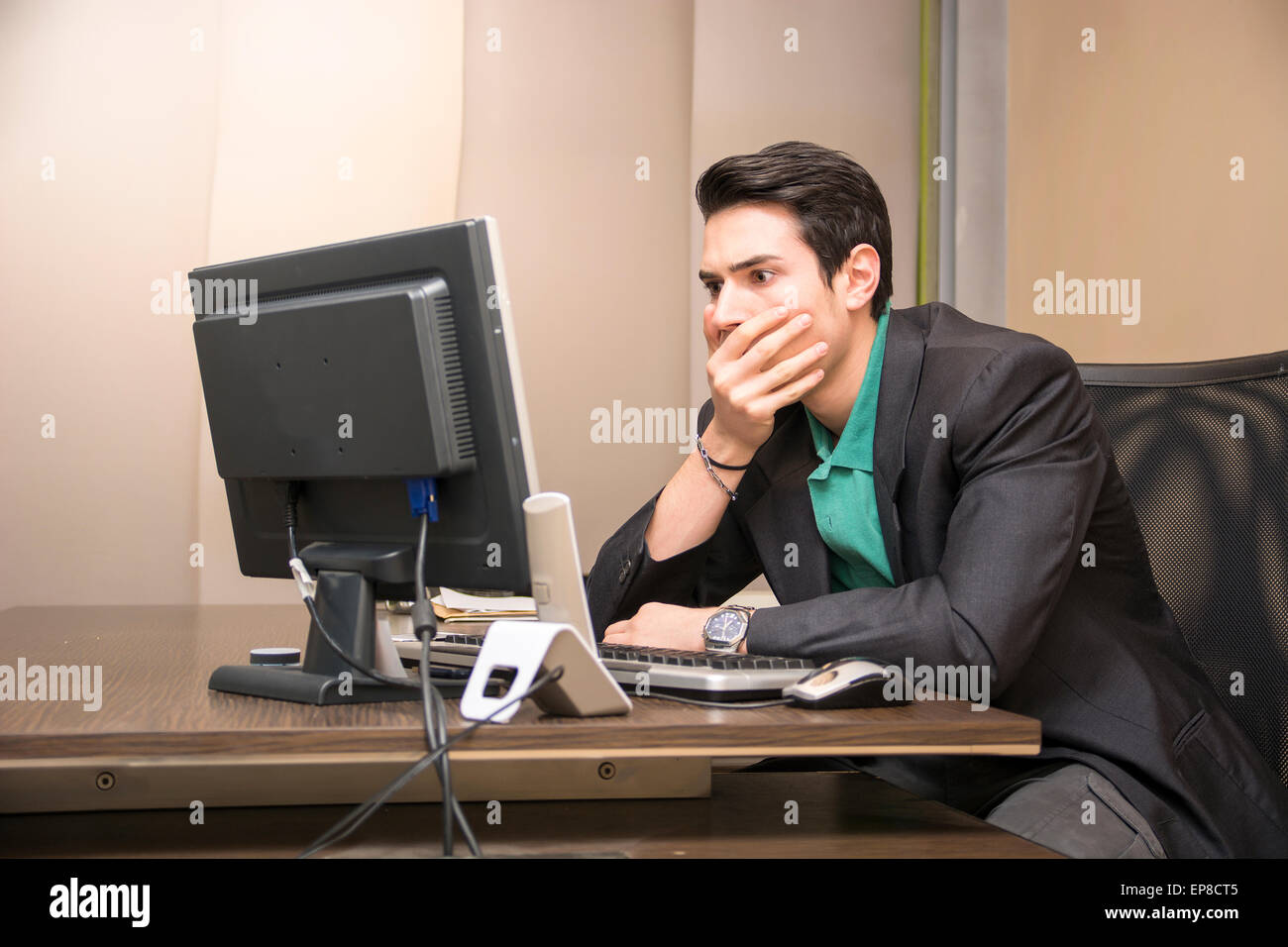 Preoccupied, worried, desperate young male worker staring at computer screen in his office Stock Photo