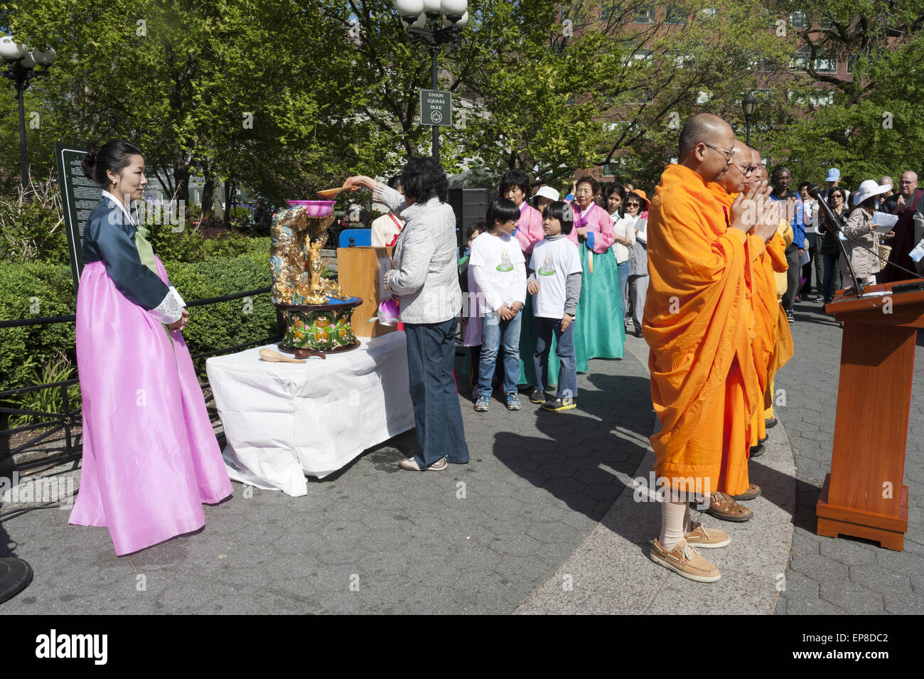 Vesak Celebration at Union Square park, NYC on May 5, 2013. Monks pray as people line up for the ceremony of Bathing the Buddha. Stock Photo