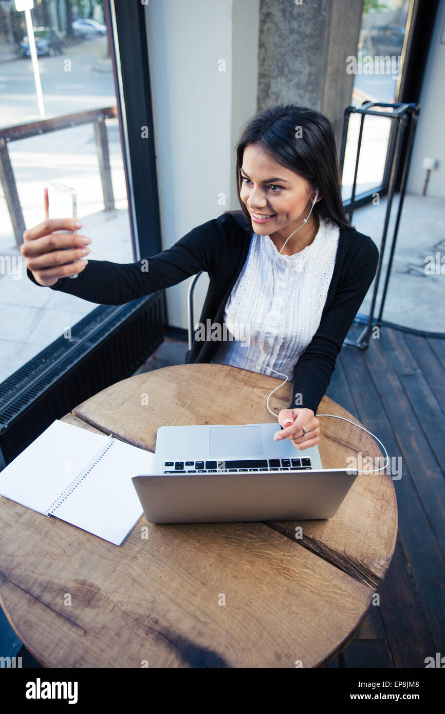 Cheerful businesswoman making selfie photo on smartphone in cafe Stock Photo