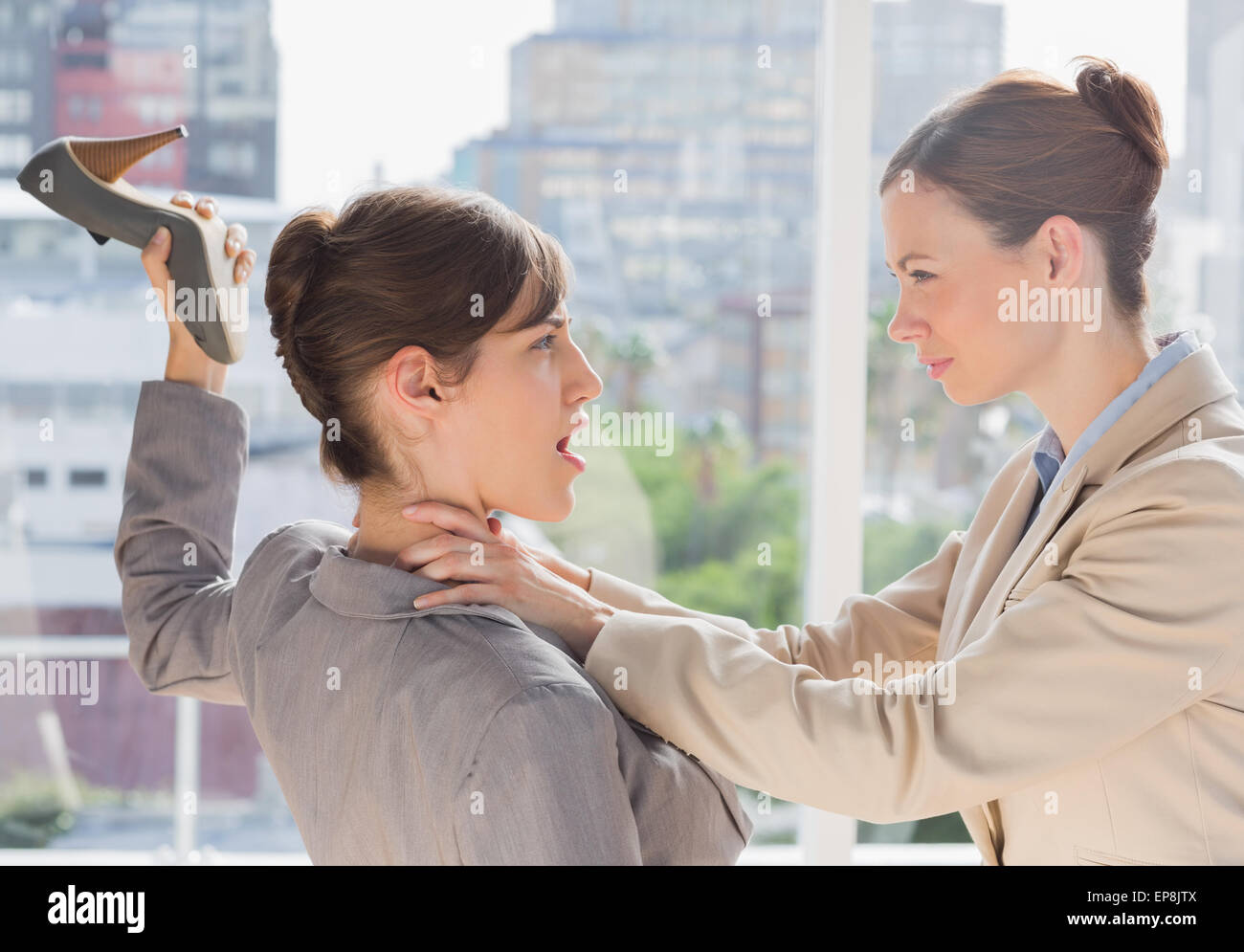 Businesswoman defending herself from her co worker strangling her Stock Photo